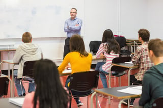 Rear view of students attentively listening to male teacher in the classroom.jpeg